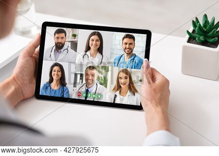 Physician Making Group Video Call With Colleagues Using Tablet Indoor
