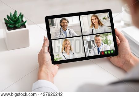 Female Doctor Having Virtual Meeting With Group Of Colleagues Indoor