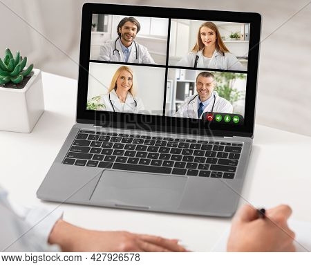 Professional Doctors Having Meeting Via Video Call On Laptop Indoor