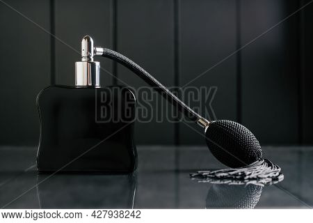 Black Bottle Of Eau De Toilette Or Perfume With Long Tassel Spray Pomp Stands On Dark Background On 