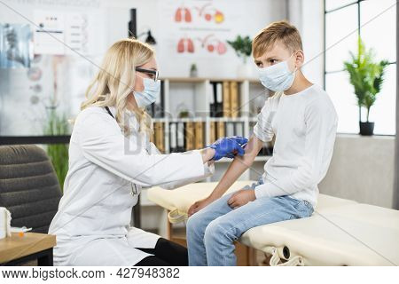 Female Doctor In Medical Mask, Gloves And Eyeglasses Doing Vaccination For Coronavirus To Male Patie