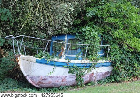 Wreck Of An Abandoned Boat Submerged In The Spontaneous Vegetation Of The Jungle That Has Taken Over