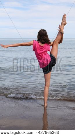 Caucasian Girl Performing Rhythmic Gymnastics Exercises With The Leg Up And The Foot Over The Head B