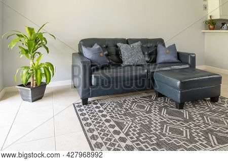 An Angled View Of A  Large Blue Moden Styled Love Seat And Ottoman Sofa Made Of Genuine Leather. The