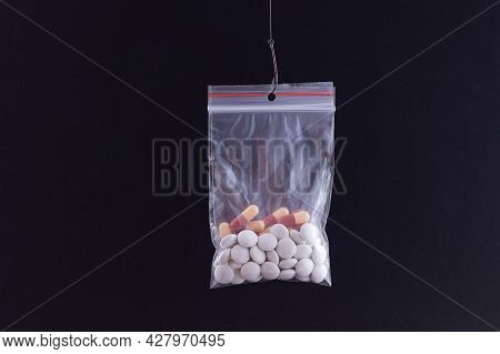 The Pharmaceutical Trap And Drug Addiction - Colored Pills Or Tablets Hanging In Small Ziplock Bag O