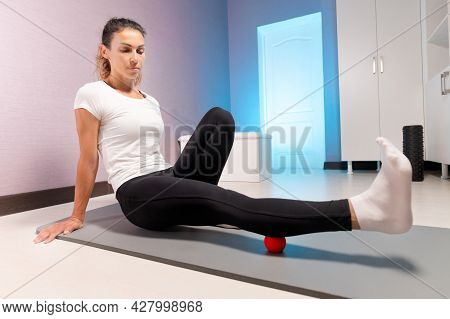 Sporty Slim Caucasian Woman Doing Self Massage On Fitness Mat With Massage Ball Indoors. Self-isolat
