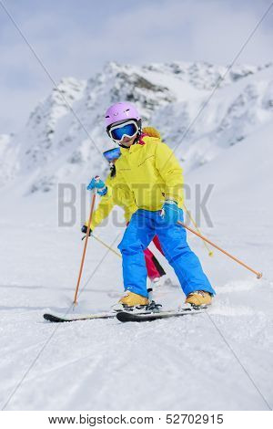 Skiing, skiers on ski run - child skiing downhill