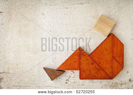 abstract sitting or relaxing figure built from seven tangram wooden pieces, a traditional Chinese puzzle game, rough white painted barn wood background
