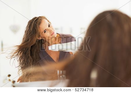 Junge Frau Blow Trocknen Haare im Badezimmer
