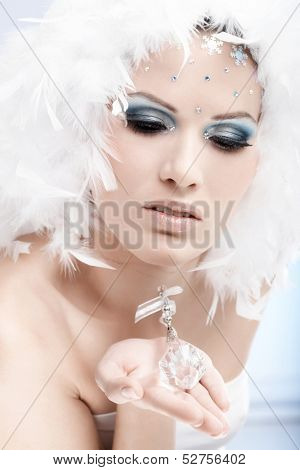 Portrait of winter beauty holding crystal gem, wearing professional makeup with strasses.