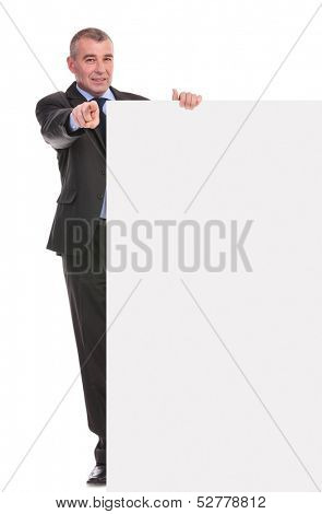 full length portrait of a business man presenting a blank pannel and pointing at the camera. on a white background