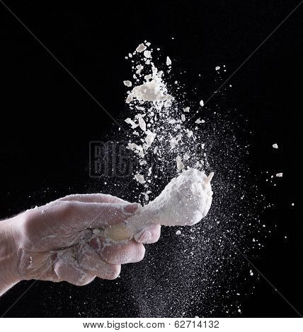 Chicken meat with flour in freeze motion, isolated on black background