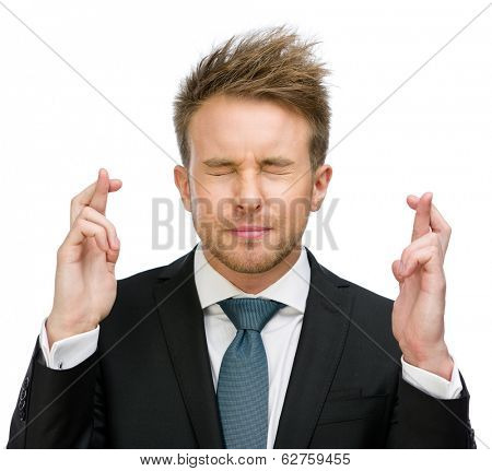 Half-length portrait of businessman with fingers crossed and eyes closed, isolated on white