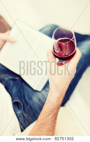 leisure, drinks, education and lifestyle concept - close up of male hand holdind book and glass of red wine