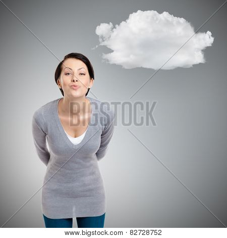 Beautiful lady throws a kiss and hides hands behind the back, isolated on grey background with cloud