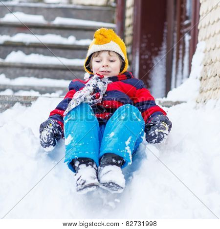 Happy Child In Colorful Clothes Having Fun With Riding On Snow, Outdoors