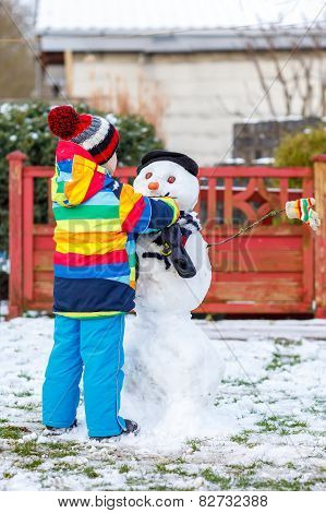 Funny Kid Boy In Colorful Clothes Making A Snowman