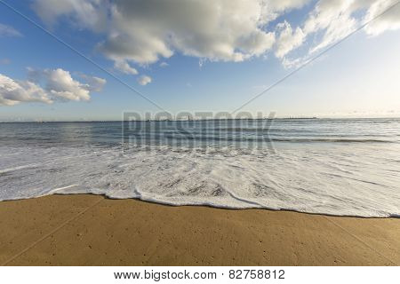 Close View Of A Foamy Wave Moving Around In The Sand On The Beach