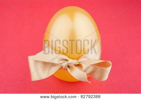 Golden egg with gift bow on red