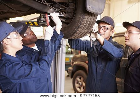 Teacher Helping Students Training To Be Car Mechanics