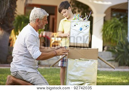 Grandfather And Grandson Building Model Robot In Garden