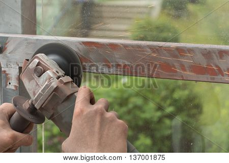 Person grinds with one-handed angle metal outdoors