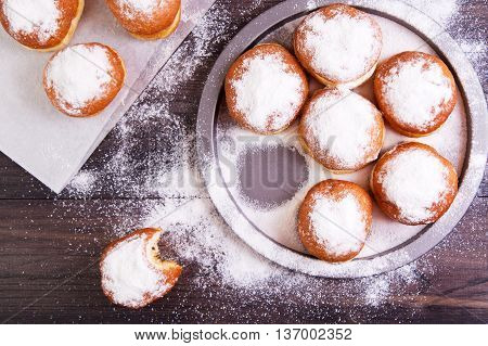 German donuts - berliner with jam and icing sugar in a tray on a dark wooden background. Top view