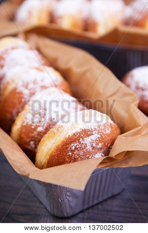 German donuts - berliner with jam and icing sugar in a box on a dark wooden table