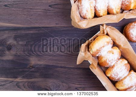 German donuts - berliner with jam and icing sugar in a box on a dark wooden background. Top view with copy space