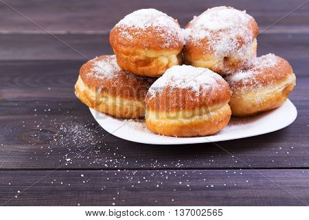 German donuts - berliner with icing sugar on plate on a dark wooden background