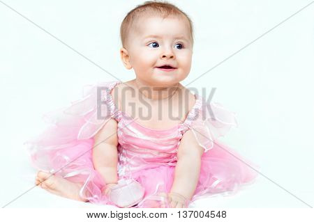 Adorable little baby girl in pink dress playing with her pink shoe indoor shot