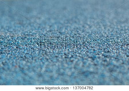 Colorful blue Rubber Wetpour playground floor surface, shot low down with narrow depth of field.