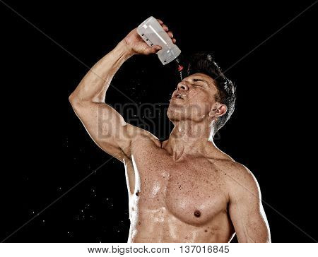 attractive strong sport man pouring water on his face sweating tired after training hard on gym bodybuilding workout isolated on black background in health care hydration and fitness concept