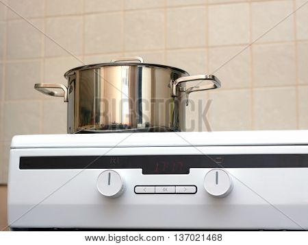 Metal steel saucepan with lid on modern kitchen electric stove. Photo closeup