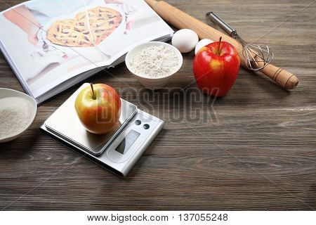 Apple with digital kitchen scales on wooden table. Cooking apple cake concept