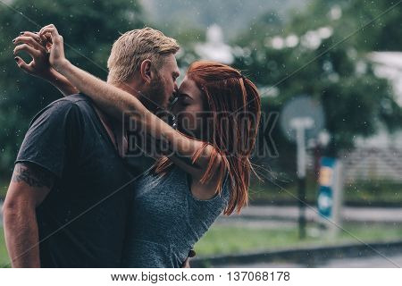 beautiful couple kissing outside in the rain