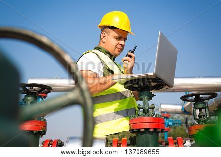 Engineer in worker's gear inspecting a valve