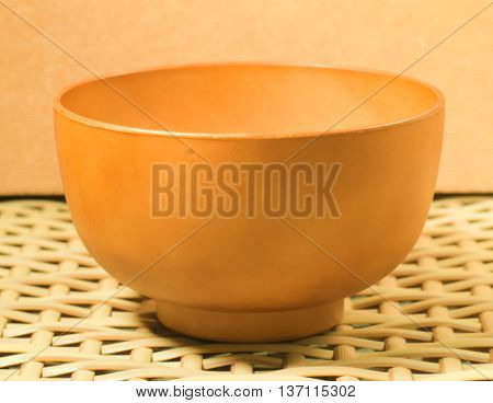 Brown wooden soup bowl on a woven bamboo chair