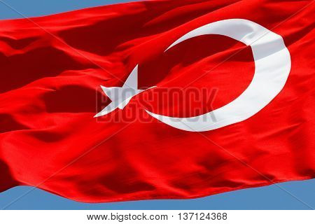 Red Turkish flag with a star and crescent on a blue sky