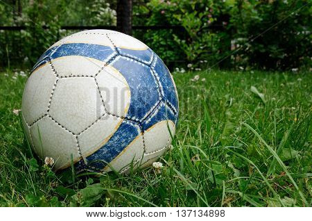 old soccer ball in the green grass on the lawn