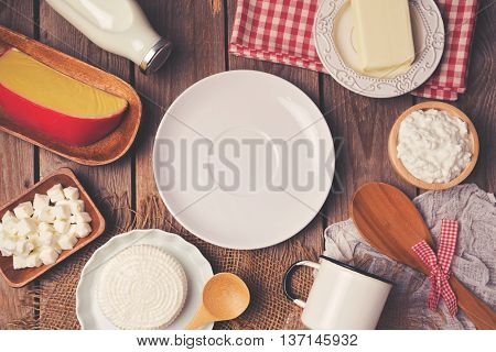 Empty plate with milk cheese and butter on wooden background. View from above. Flat lay