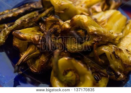 Closeup spicy grilled cubanelle hot peppers on blue plate