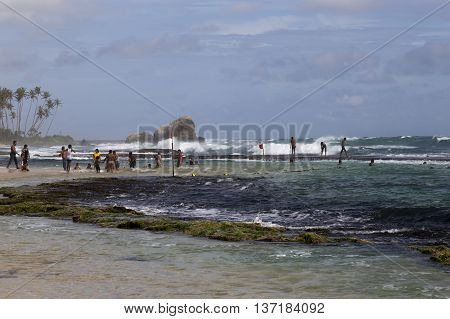 The coast having a rest and swiming people on the religious holiday Vap Poya on Sri Lanka