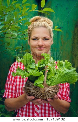 Blonde girl on a green background holding basket with lettuce. Rockabilly style. Space for text