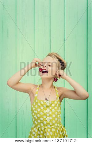 Beautiful girl holding cherries as earrings -style Rockabilly. Space for text