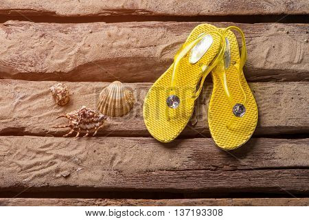 Flip flops and seashells. Yellow flip flops on sand. Travel and explore the world. Exciting adventures are waiting.