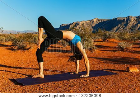 Young woman doing yoga in desert at sunset time