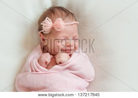smiling newborn baby sleeping on white blanket
