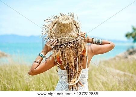 Attractive boho style woman in straw hat. Back view