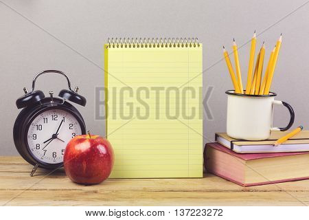 Notebook with pencils and book on wooden table. Back to school concept